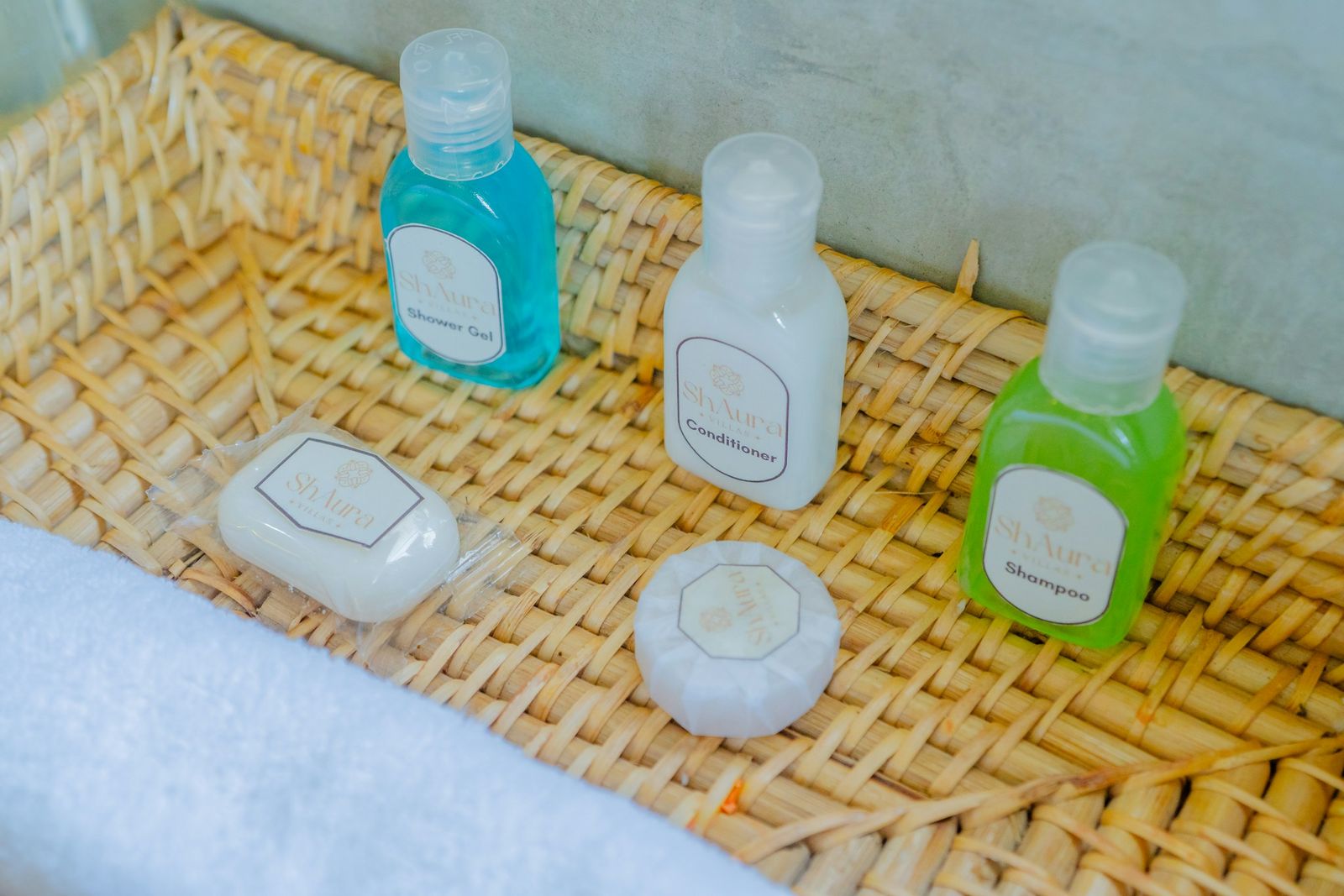 Travel size shampoo, shower gel and soap arranged in a woven basket